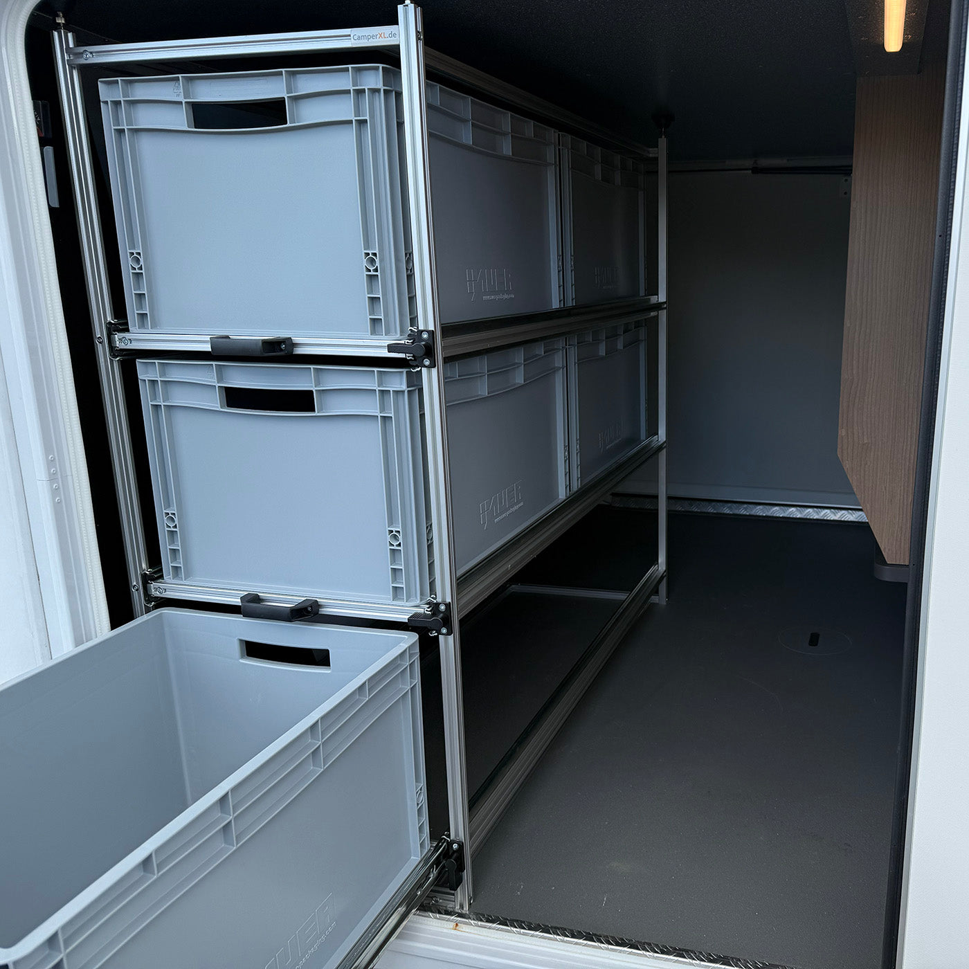 Aufgeräumte Heckgarage im Malibu Wohnmobil mit ausziehbarem Regal und sortierten Euroboxen