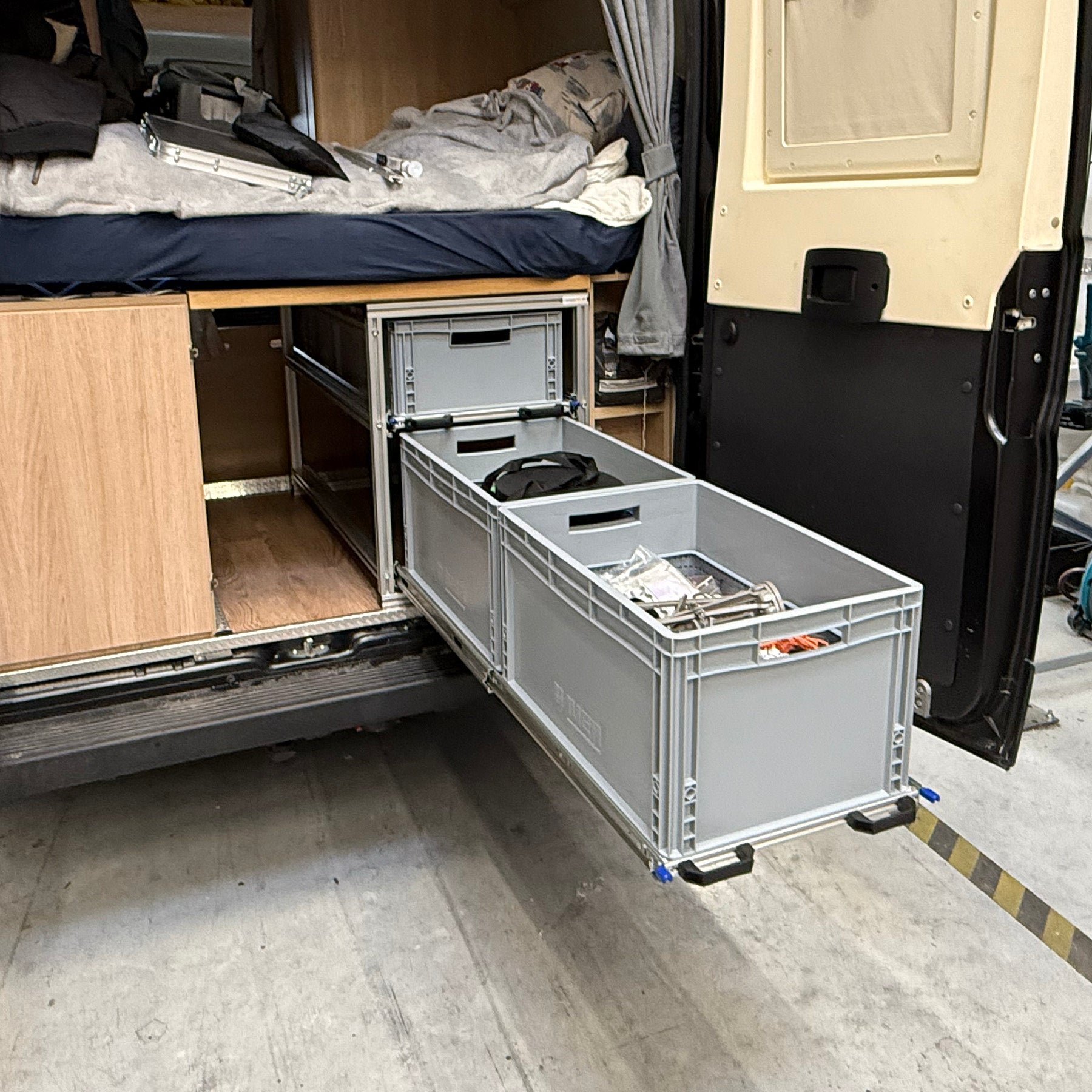 Ausziehbares Regalsystem im Fahrzeugheck mit zwei Ebenen für Euroboxen, unterstützt durch belastbare Verriegelungs­auszüge.